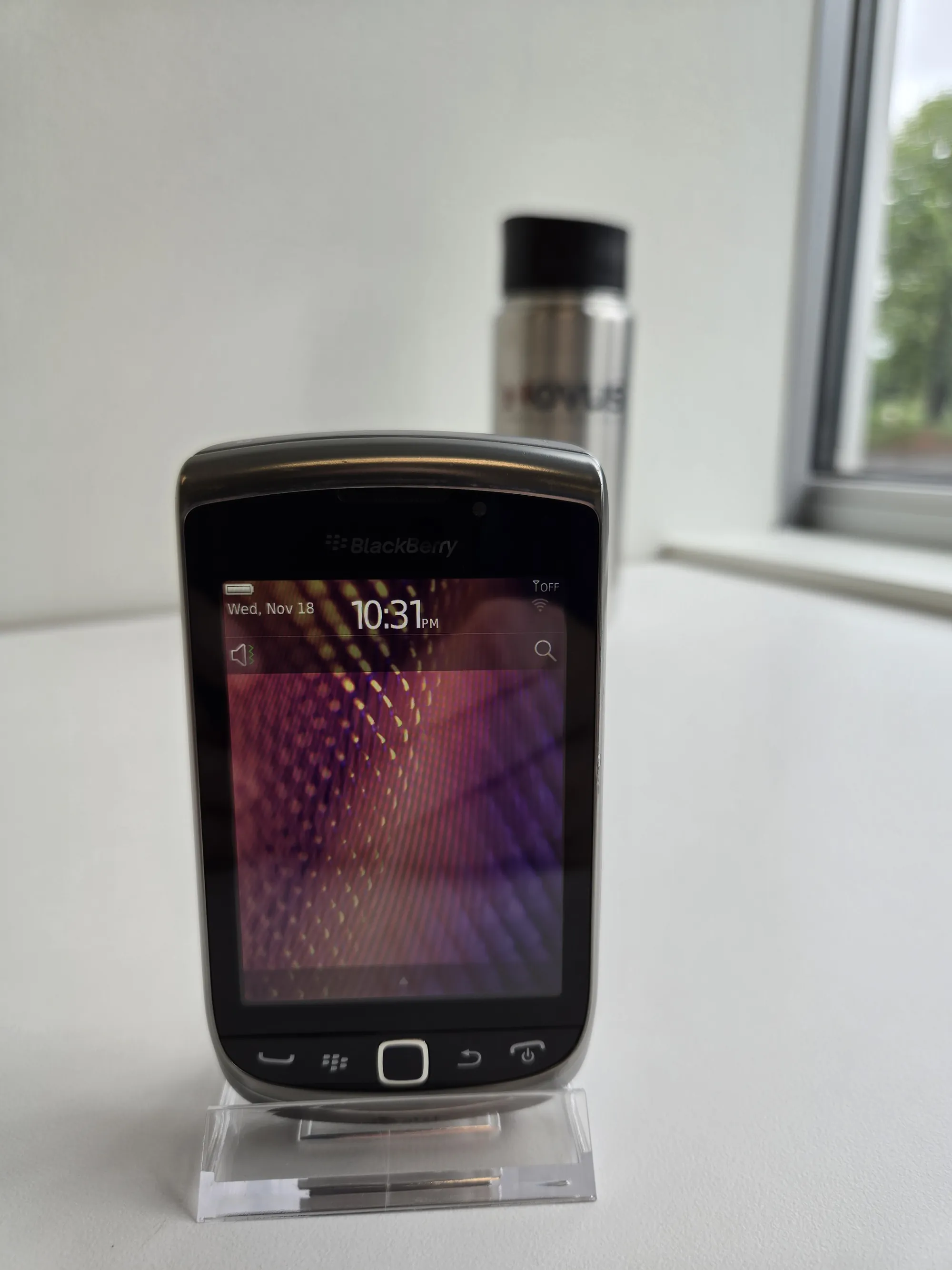 BlackBerry Torch 9810 front view, slider closed, on a display stand